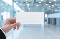 Hand holding blank name card paper showing ceiling.