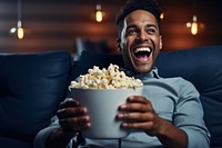 Man holding popcorn laughing smiling adult. 