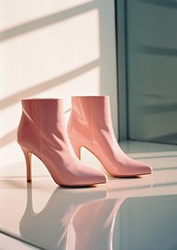A pair of high heel boots sitting in front of a mirror footwear shoe clothing. 