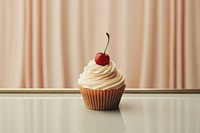A cupcake with whipped cream and a cherry on top with mirror dessert fruit food.