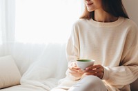 Woman holding a cup of matcha tea sweater sitting coffee. AI generated Image by rawpixel.