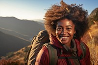 African woman hiking mountain backpack smiling.
