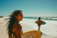 Latina woman carrying surfboard with her friend on the beach portrait outdoors surfing. 