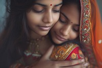 Portrait of two indian women wedding hugging adult.