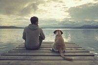 Indian man sitting with dog on jetty portrait outdoors nature.
