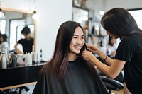 Smiling hairdresser doing haircut for south east asian woman adult electronics hairstyle.