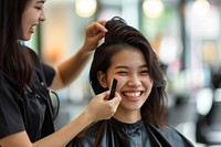 Smiling hairdresser doing haircut for south east asian woman adult hairstyle happiness.