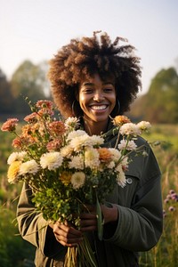 Black woman holding bouquet flower portrait outdoors smiling.