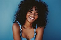 South african woman with a wig and curly hair wearing blue dress photography portrait laughing.