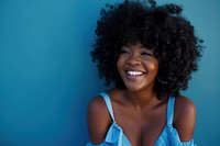 South african woman with a wig and curly hair wearing blue dress laughing smile happy.