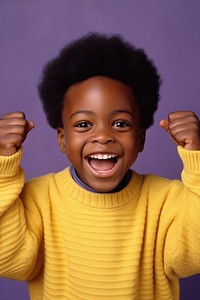 African boy with his hands up sweater laughing yellow.