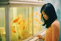 A asian woman looking in the gold fish tank aquarium animal adult. AI generated Image by rawpixel.