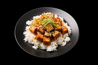 A rice and fried tofu with sesame seeds on the black plate food meal meat.