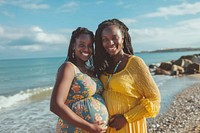 Happy black pregnant woman standing with mother at beach outdoors adult happy.