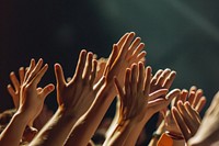 A group of hands reaching up and holding on to each other concert finger performance.