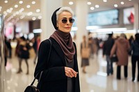 A senior Iranian woman shopping in the department store during discount time scarf adult coat.