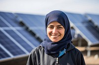 A solar Iranian woman worker smiles in front of solar panels happy environmentalist architecture.