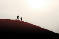 Man pulling up friend silhouette adventure outdoors.