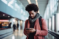 Black young man at the airport looking at the list of destinations holding a cell phone adult transportation architecture.