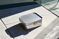 A stainless steel lunch box silicone lid and white silicone strap  architecture container metal.