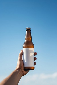 Holding beer bottle with blank white label drink blue sky.