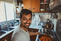 Indian father cooking food smiling adult.