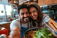Indian couple cooking food smiling selfie.