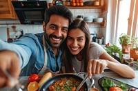 Indian couple cooking food smiling selfie.