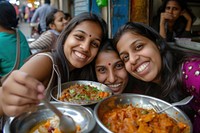 Indian girls eating food restaurant smiling.