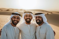 3 Middle eastern men in thawb laughing outdoors smiling.