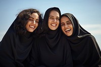 3 Middle eastern women laughing outdoors smiling.