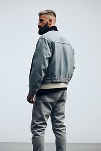 A man in jeans looking up on a white background isolation back view standing jacket pants.