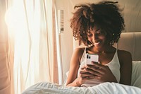 African American young woman bedroom mobile phone portability.