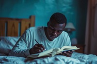 Black man writing bed furniture.