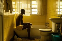 Black South African man bathroom bathtub sitting.