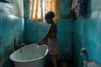 Black South African woman bathroom cleaning bathtub.