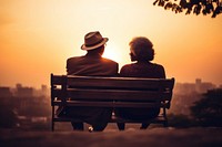 Senior black couple sitting sunset bench.