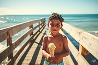 Latino boy holding an ice cream on a boardwalk against ocean background vacation summer child. AI generated Image by rawpixel.