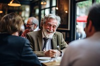 Senior gentleman engaged in a lively conversation with friends at a local cafe laughing adult mug. AI generated Image by rawpixel.