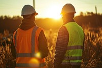 Diverse construction workers talking sunlight outdoors hardhat.