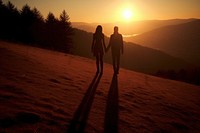 Tourists holding hand on the hill in the sunrise walking shadow holding hands.