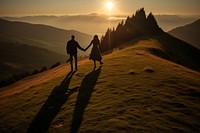 Tourists holding hand on the hill in the sunrise shadow adult holding hands.