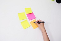 Female writing new ideas on sticky note pen white background organization. AI generated Image by rawpixel.