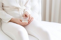 Pregnant woman holding drinking glass and medicine sitting on bed refreshment relaxation midsection. AI generated Image by rawpixel.