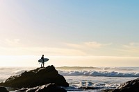 Surfer on rock looking at ocean outdoors horizon nature.