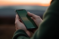 Holding smart phone outdoors sunset photo.