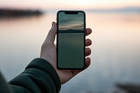 Holding smart phone outdoors sunset photo.