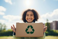 Holding recycle box outdoors smiling child.