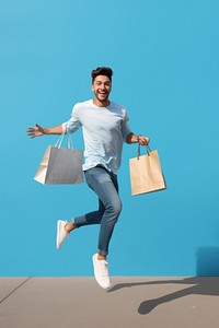 Happy young hispanic man jumping and holding a shopping bag adult men architecture.