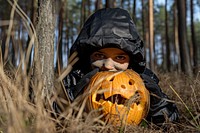 A kid with funny costume holding halloween pumpkin jack-o'-lantern anthropomorphic jack-o-lantern.